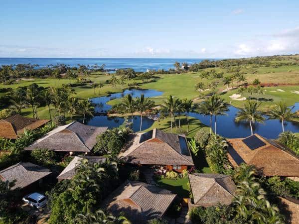 Tropical resort with villas, palm trees, and ocean view in lush green landscape.